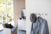 White Wall-Mounted Coat Hanger holding hat and jacket by Yamazaki Home.