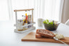 White Countertop Storage Caddy holding spices and oil on dining table by Yamazaki Home.