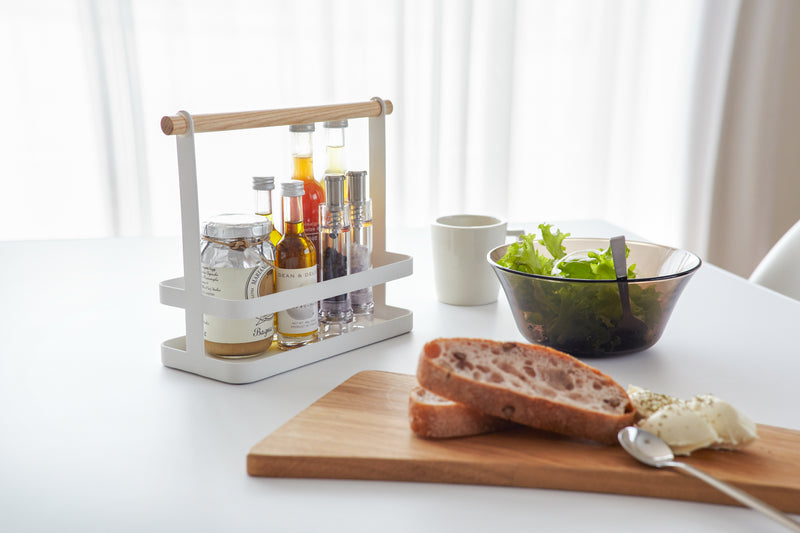 White Countertop Storage Caddy holding spices and oil on dining table by Yamazaki Home.