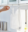 White kitchen Undershelf Hangers holding recycling bag by Yamazaki Home.