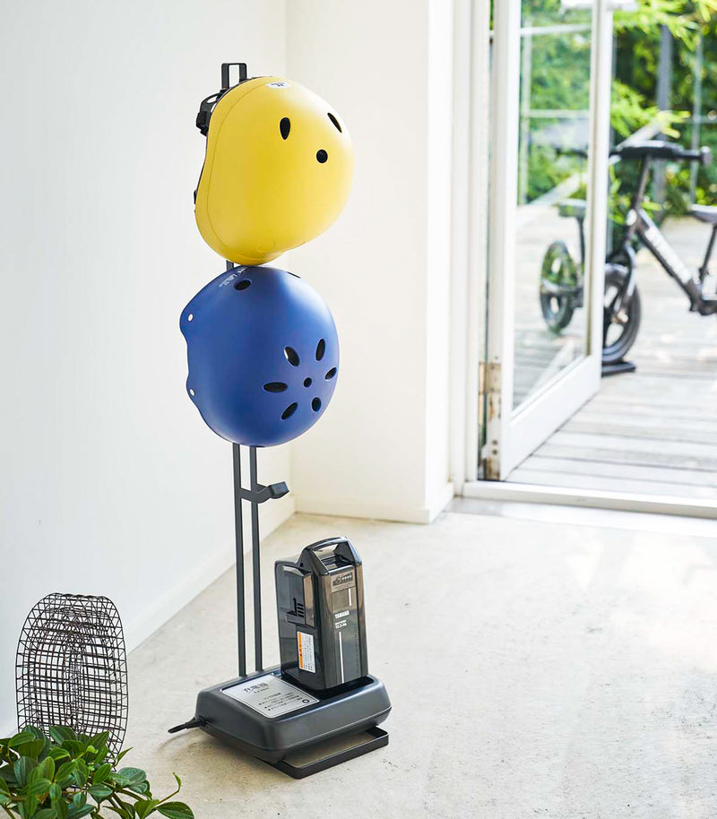 Black Kids' Helmet Stand holding helmets and bike gear by Yamazaki Home.