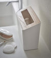 Side view of White Countertop Waste Bin on bathroom sink countertop by Yamazaki Home.