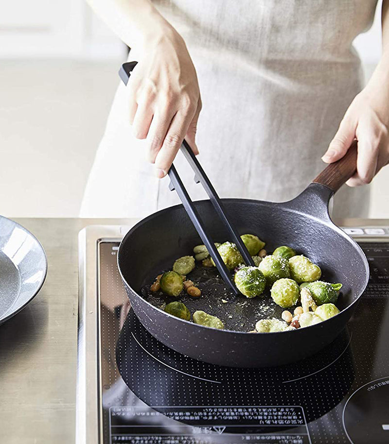 Front view of black Floating Tweezer Tongs cooking in kitchen by Yamazaki Home.