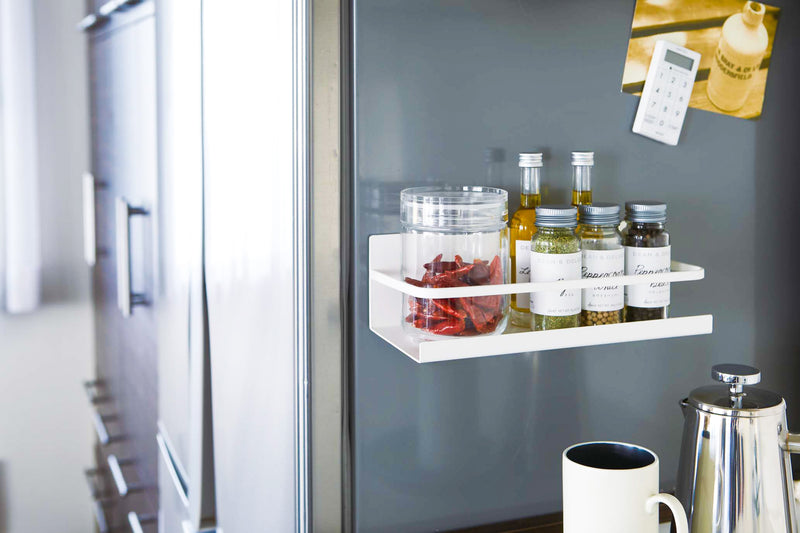 White Magnetic Storage Caddy holding spices in kitchen by Yamazaki Home.