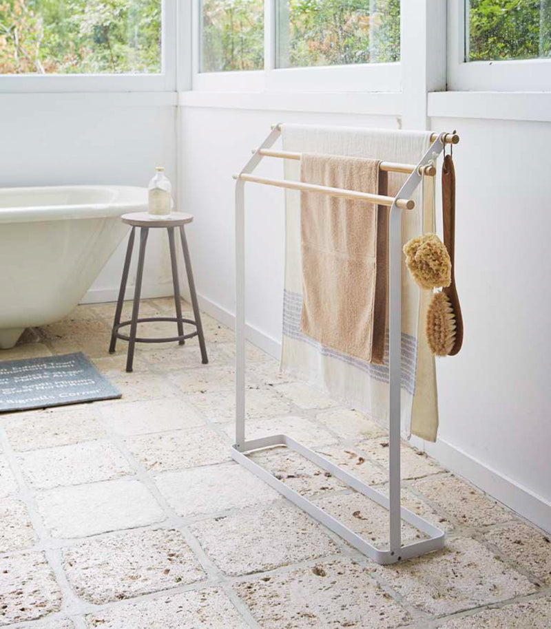 Bath Towel Rack holding towels and brushes in bathroom by Yamazaki Home.