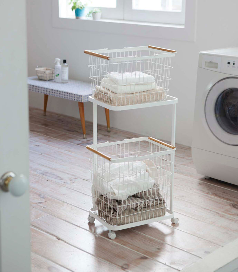 White Laundry Wagon and Basket holding clothes in laundry room by Yamazaki Home.