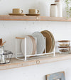 Wood-Accented Dish Storage Rack holding plates on kitchen shelf by Yamazaki Home.