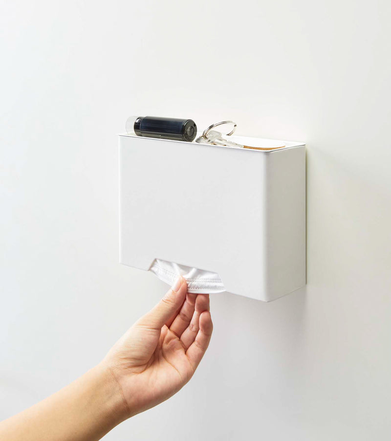 Front view of white Face Mask Dispenser holding keys and dispensing masks by Yamazaki Home.