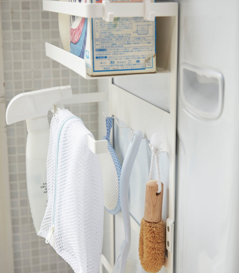 Close up side view of white Magnet Laundry Storage Pockets holding cleaning items by Yamazaki Home.