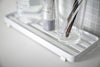 Close up view of white Slotted Tray holding sink accessories in bathroom by Yamazaki Home.