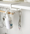 Close up of white Undershelf Hanger holding cleaning supplies by Yamazaki Home.