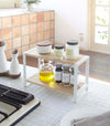 White Countertop Shelf on kitchen counter holding spices and oil by Yamazaki Home.