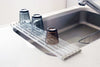 Blue pot and yellow knife sitting on White Yamazaki's over-sink drying rack.
