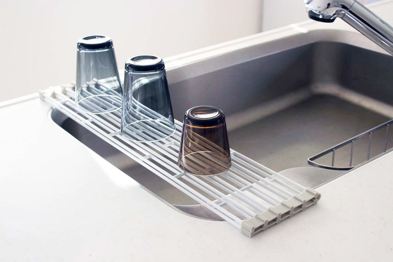 Blue pot and yellow knife sitting on White Yamazaki's over-sink drying rack.
