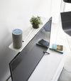 Aerial view of white Compliant TV Shelf holding smart home device, remote, and plant behind TV by Yamazaki Home.