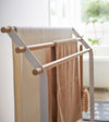 Close up side view of Bath Towel Rack holding towels in bathroom by Yamazaki Home.