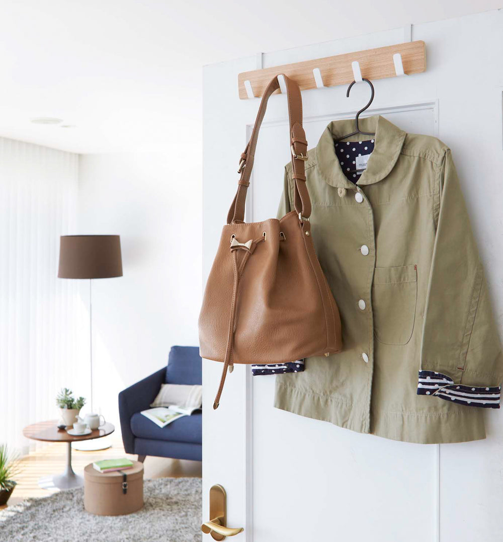 White Over-the-Door Hanger displaying purse and jacket on door by Yamazaki Home.
