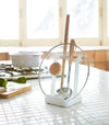 White Lid & Ladle Stand holding pot cover and kitchen utensils on kitchen countertop by Yamazaki Home.
