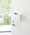 White Face Mask Dispenser holding keys on door by Yamazaki Home.