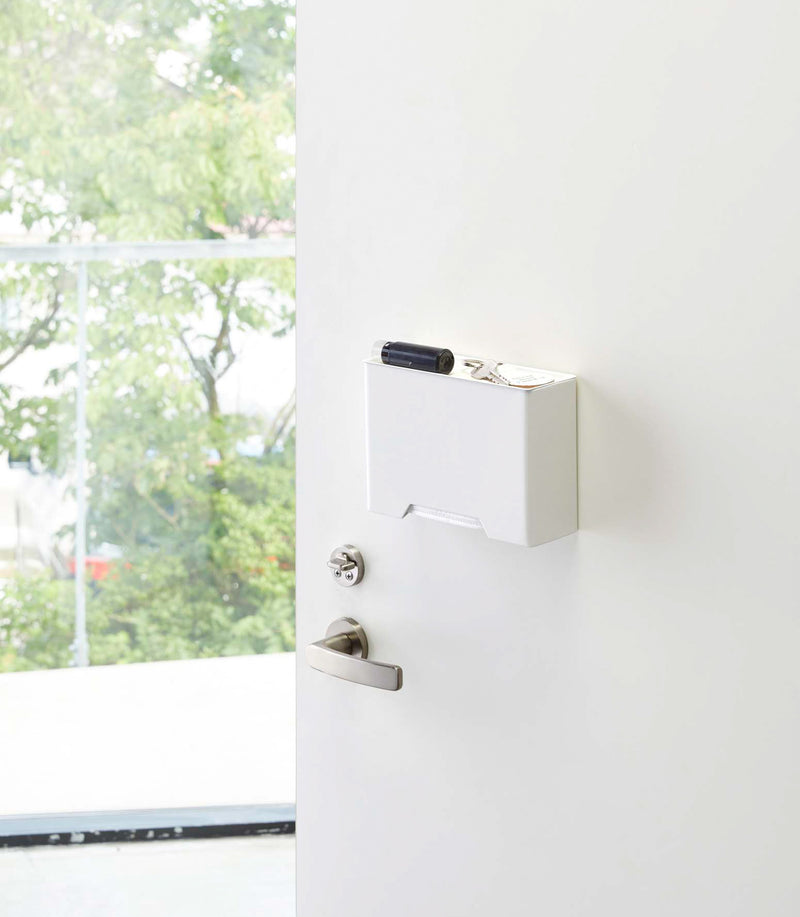 White Face Mask Dispenser holding keys on door by Yamazaki Home.