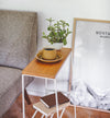 Side view of white End Table holding coffee cup, plant, and books by Yamazaki Home.
