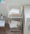 Front aerial view of white Laundry Wagon and Basket holding clothes and towels in laundry room by Yamazaki Home.