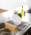 Over-the-Sink Dish Drainer holding dishes and silverware in kitchen by Yamazaki Home.