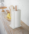 Paper Towel Holder holding paper towel on shelf in kitchen by Yamazaki Home.
