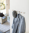 White Wall-Mounted Coat Hanger displaying hat and jacket by Yamazaki Home.